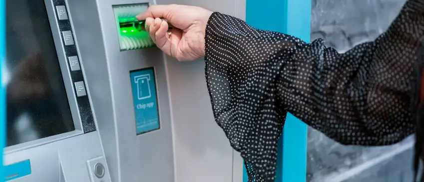 Kvinnas hand tar ut bankkort från automat